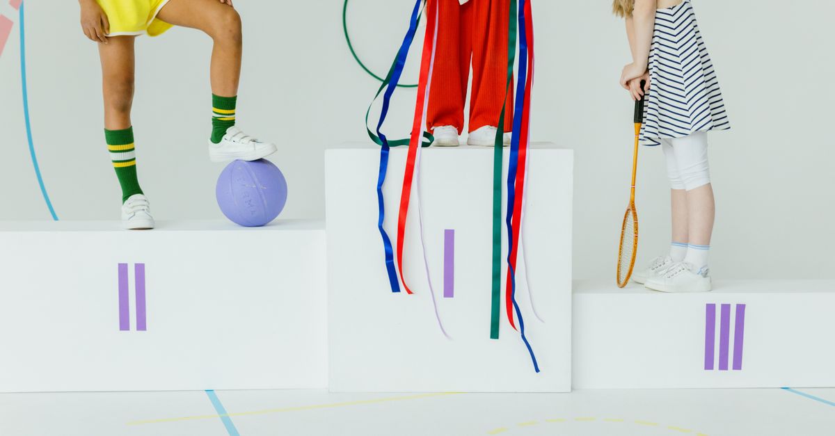 Children standing on a podium with sports equipment in a playful setting.
